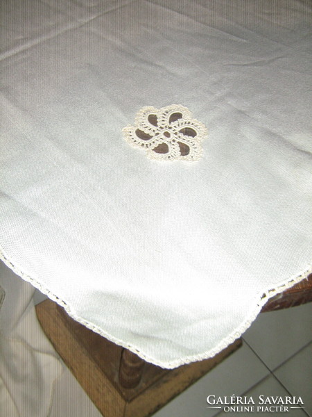 A cream-colored tablecloth with a beautiful hand-crocheted flower insert