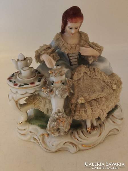 Old lacy baroque style porcelain figurine of a lady playing with a dog.