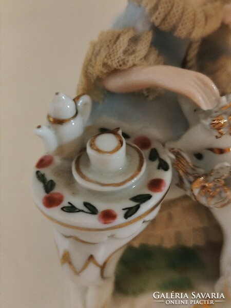 Old lacy baroque style porcelain figurine of a lady playing with a dog.