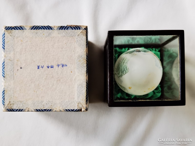 Old Chinese hand-painted egg in wooden holder behind glass