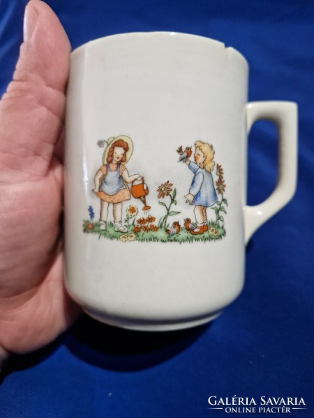 An old Zsolnay porcelain mug depicts two little girls, a fairy mug with a scene