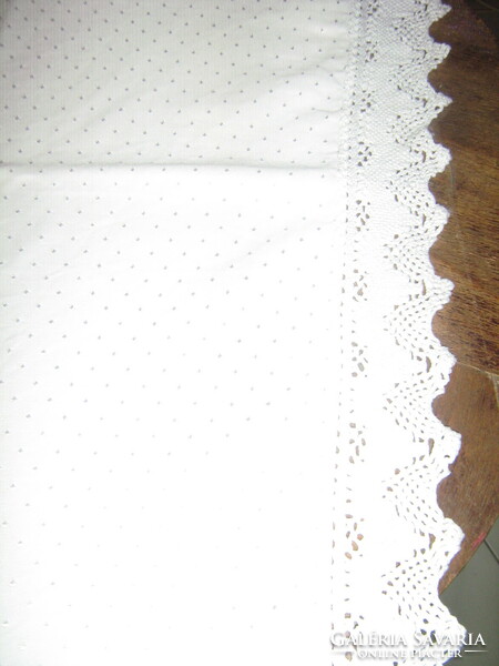 Beautiful snow-white elegant damask tablecloth with shiny spots and lace edges