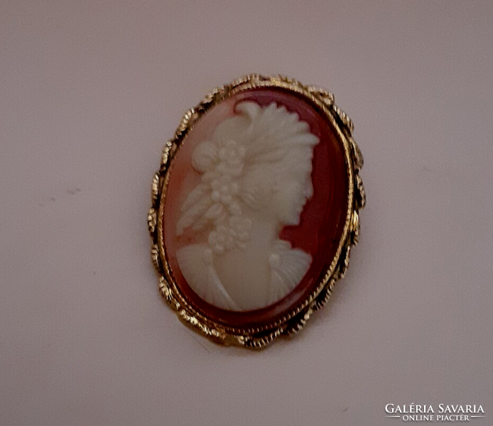 Brooch pin studded with a carved cameo in a gilded patterned frame