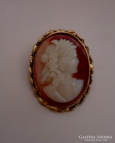Brooch pin studded with a carved cameo in a gilded patterned frame