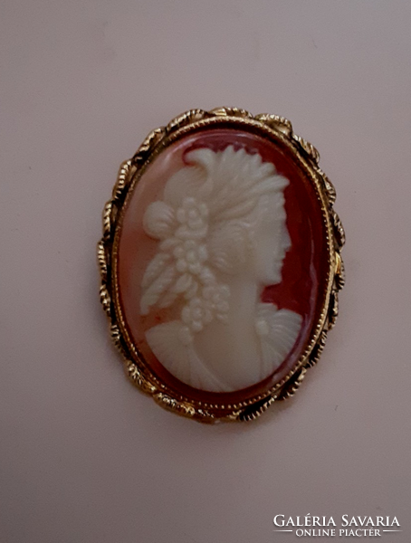 Brooch pin studded with a carved cameo in a gilded patterned frame