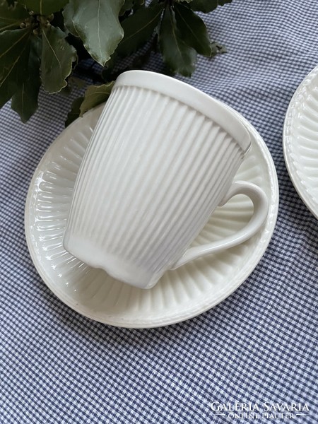 A pair of cream-colored mugs with ribbed walls and clean lines