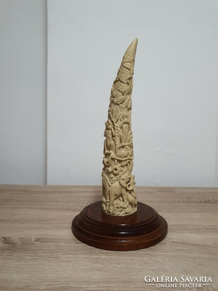 Carved elephant tusk on a sophisticated wooden base.