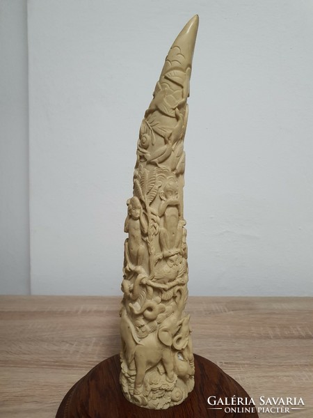 Carved elephant tusk on a sophisticated wooden base.