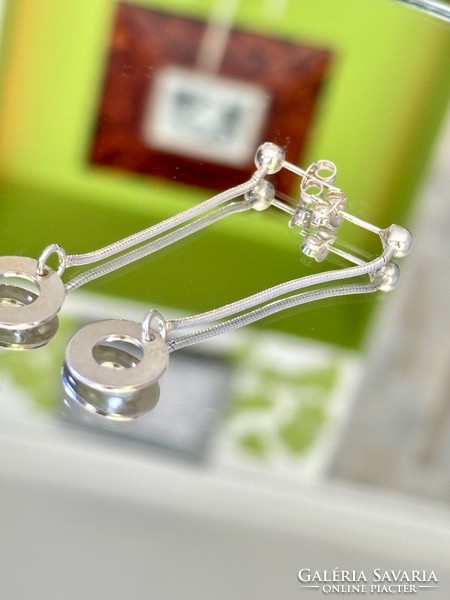 A pair of shiny, dangling silver earrings