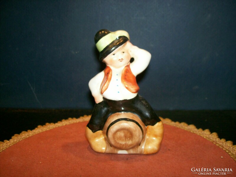 Boy figurine sitting on a ceramic wine barrel