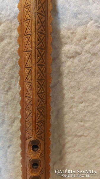 A folk wooden musical instrument with a carved tilinko