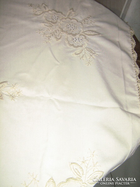 Handwork tablecloth with a crocheted edge embroidered with beige flowers on a beautiful beige background