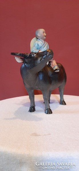 Chinese boy on the back of a buffalo with a rose in his hand. Detailed, hand-painted, 19 cm high porcelain statue.