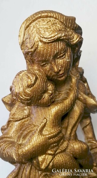 Golden Madonna with her child. Fat stone sculpture with a rustic surface