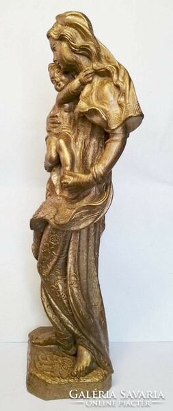 Golden Madonna with her child. Fat stone sculpture with a rustic surface