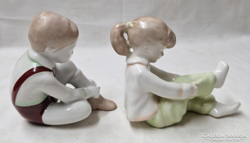 Aquincumi boy tying his shoes and girl pulling her socks porcelain figurines together in perfect condition