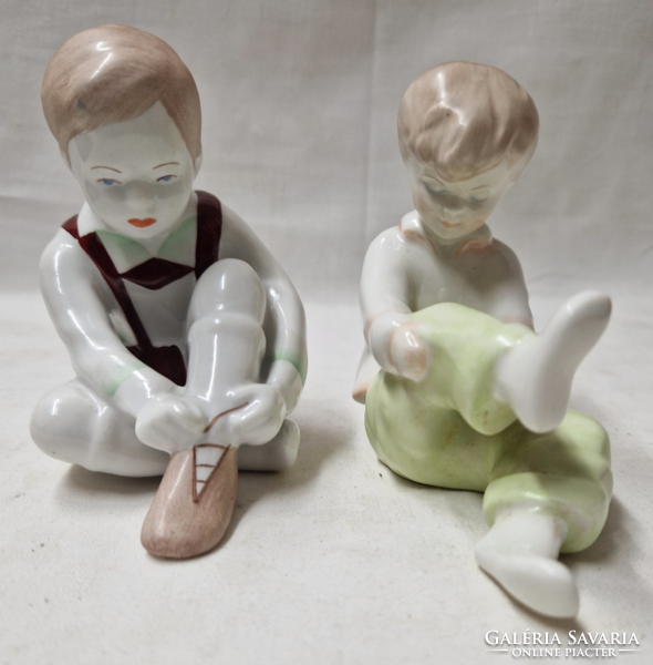 Aquincumi boy tying his shoes and girl pulling her socks porcelain figurines together in perfect condition