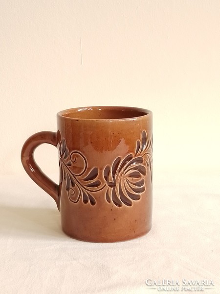 Old brown ceramic mug marked foreign, with a flower pattern printed on the material