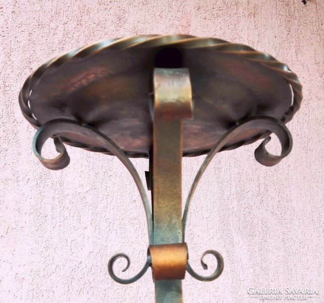 A giant forged red copper candle holder. A work of applied art, in a rustic environment.