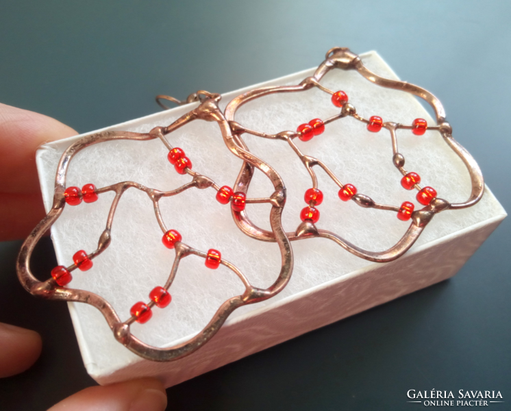 Swirling red pearl earrings soldered into a copper wire frame