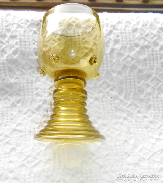 Old handmade thick-bottomed glass goblet with knotted decoration on the side.