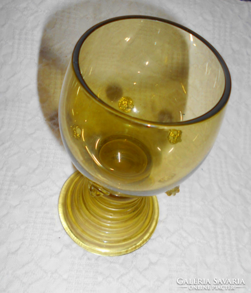 Old handmade thick-bottomed glass goblet with knotted decoration on the side.