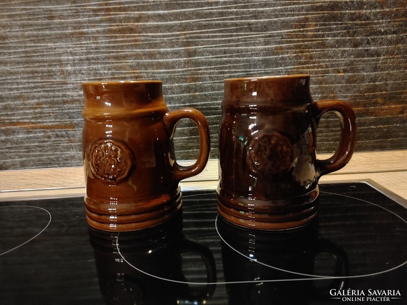 Two ceramic beer mugs, one with a green leaf frog