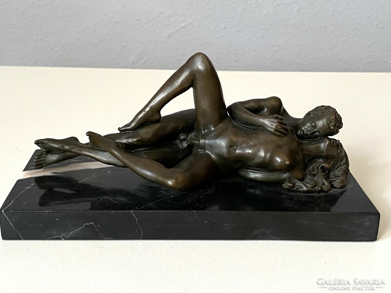 Erotic bronze statue of young people in love on a black marble base