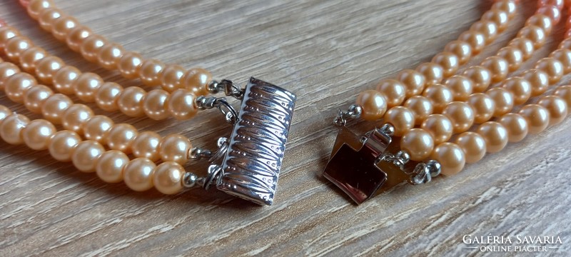 Peach-colored four-row string of pearls, neck blue