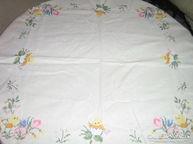 Beautiful hand embroidered cross-stitch floral chick on white tablecloth