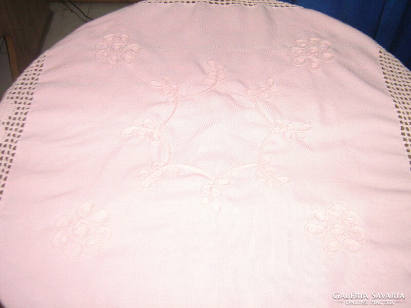 A charming hand crocheted pink tablecloth with a stitched floral edge