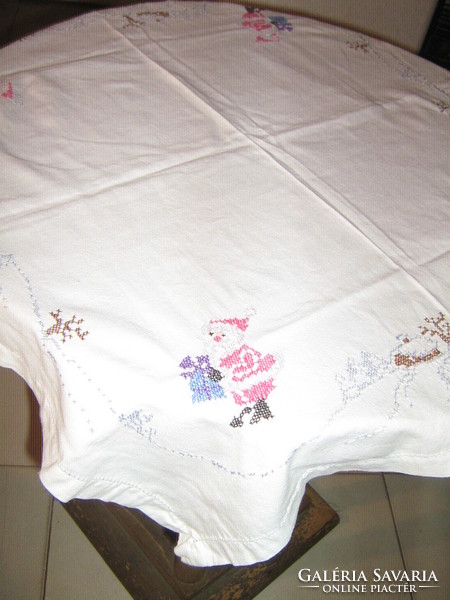 Beautiful cross-eyed hand embroidered Santa Claus on a white winter tablecloth