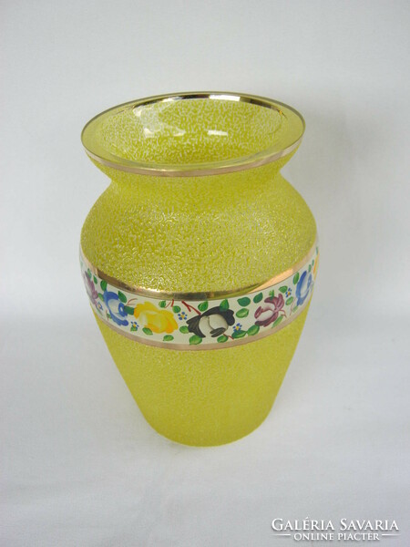 A yellow glass vase with a thick rough surface decorated with a flower painted in a circle