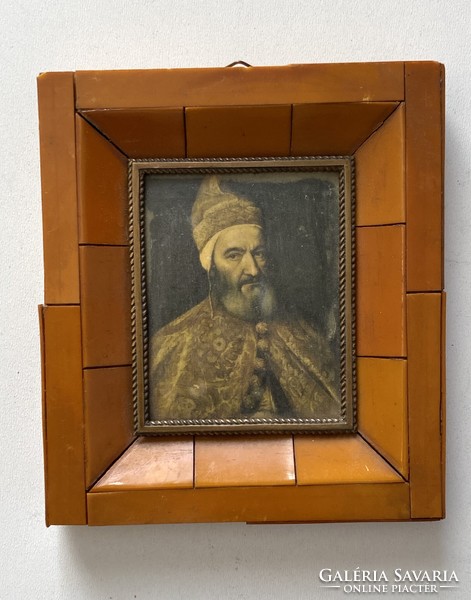 A print of an antique painting of a male portrait of Titian in an amber-colored ornate frame